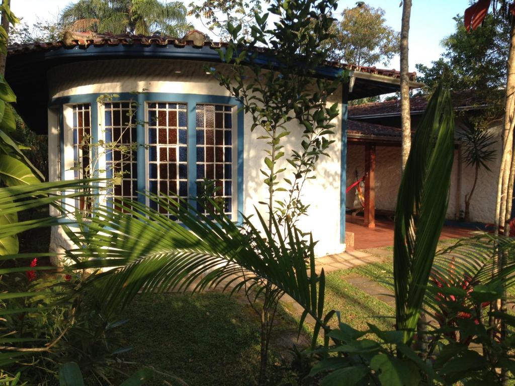 une petite maison blanche avec une fenêtre bleue dans l'établissement Casa na quadra da Praia do Tenório, à Ubatuba