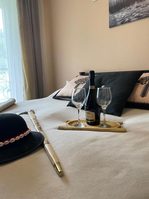 a bottle of wine and two glasses on a bed at HELLO GIEWONT in Zakopane