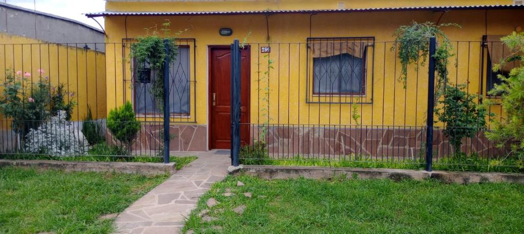 uma casa amarela com uma porta vermelha e uma cerca em La Nona em El Carmen