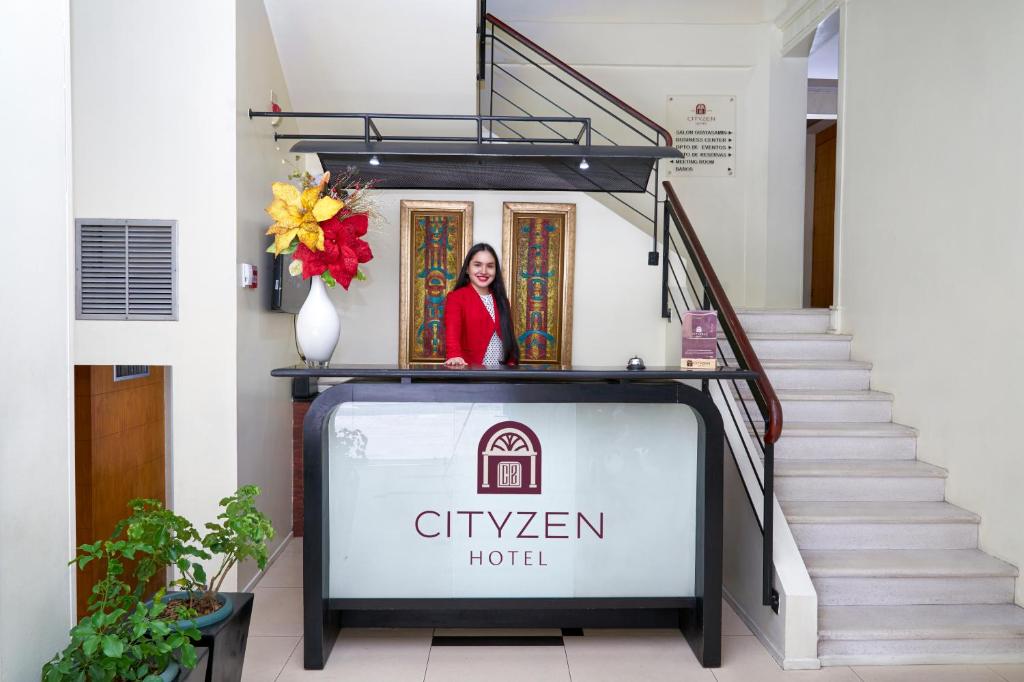 una mujer de pie detrás de un cartel en una escalera en Hotel Cityzen Guayaquil, en Guayaquil