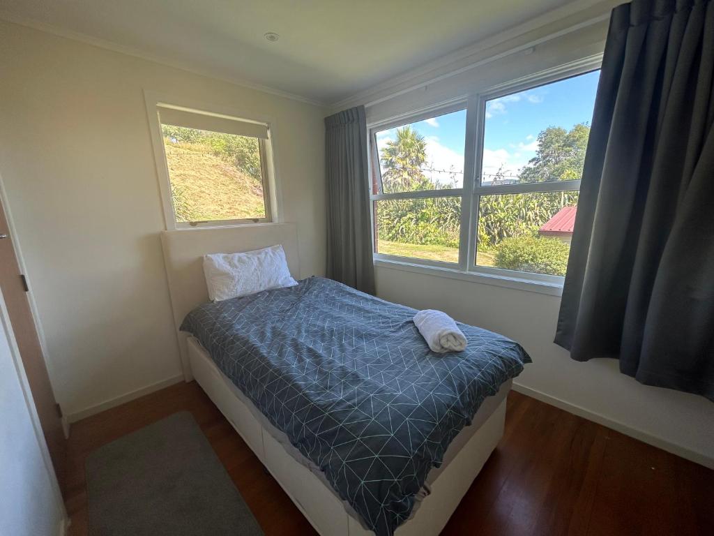 a small bedroom with a bed and two windows at Rotorua Lakes House in Rotorua