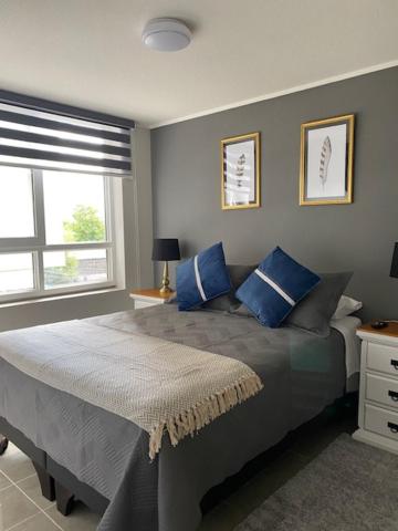 een slaapkamer met een groot bed met blauwe kussens bij Apart Center Temuco in Temuco