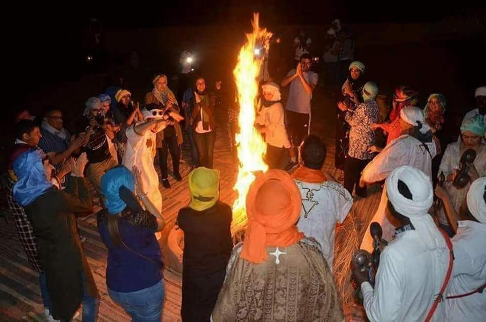grupa ludzi stojących wokół ogniska w obiekcie Mirdane Camp w mieście Merzouga