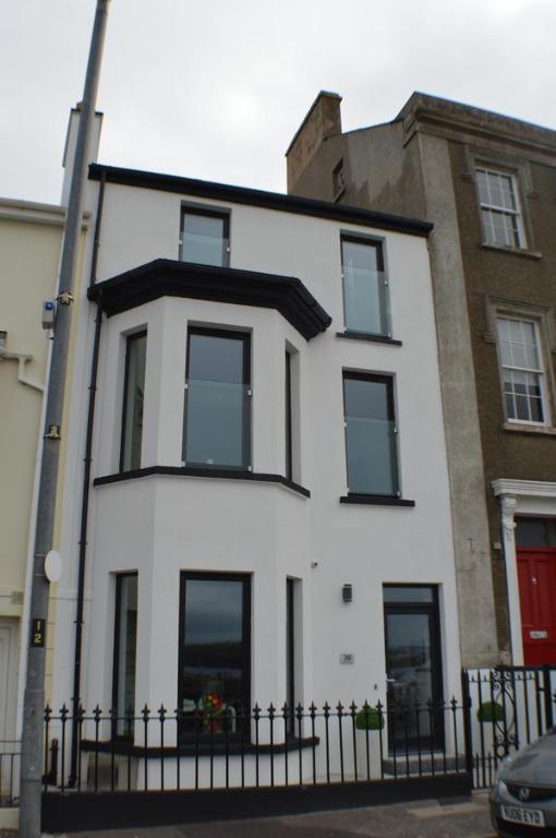 a white house with black windows and a fence at Pier39Portrush Adult Only in Portrush