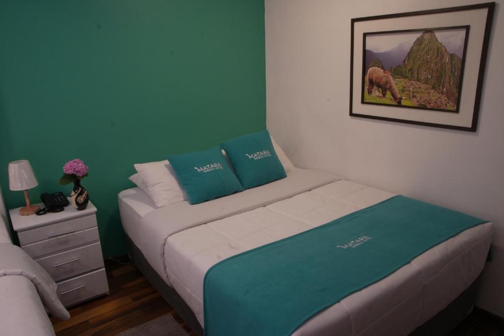a small bedroom with a bed with blue walls at MATARA GREENS HOTEL in Cusco