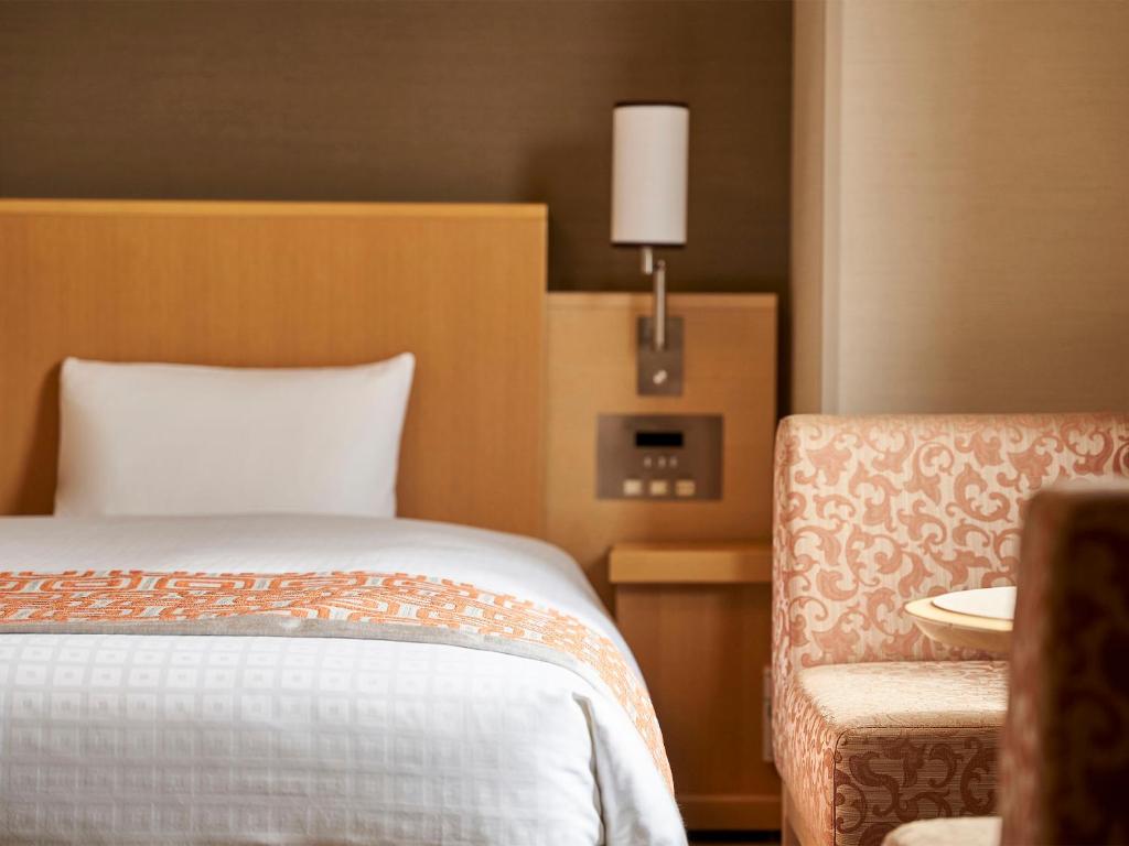 広島市にあるダイワロイネットホテル広島のベッドと椅子付きのホテルルーム