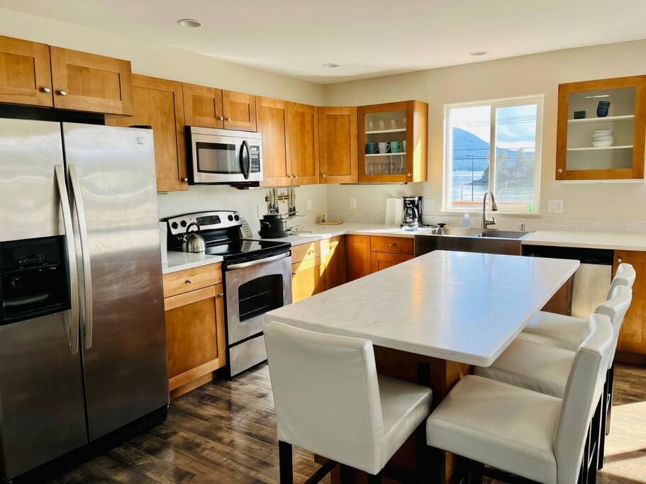 una cocina con nevera de acero inoxidable y armarios de madera en Auk Nu, Cove View Alaskan Home, en Mendenhaven