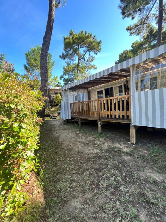 a large house with a deck and a tree at Mobilhome Luminosa tt équipé 6/8 pers in Les Mathes