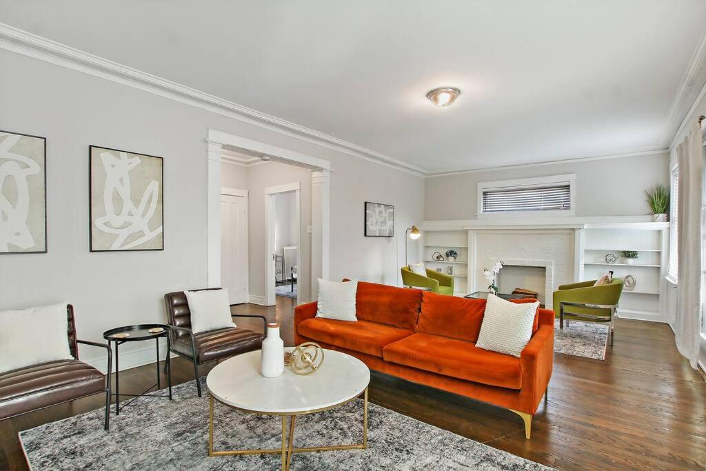 sala de estar con sofá naranja y sillas en Roomy & Inviting 3BR Chicago Apartment - 53rd St 2E, en Chicago