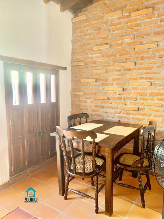 a wooden table and chairs in a room with a brick wall at Apto La Hoyo in Mompós