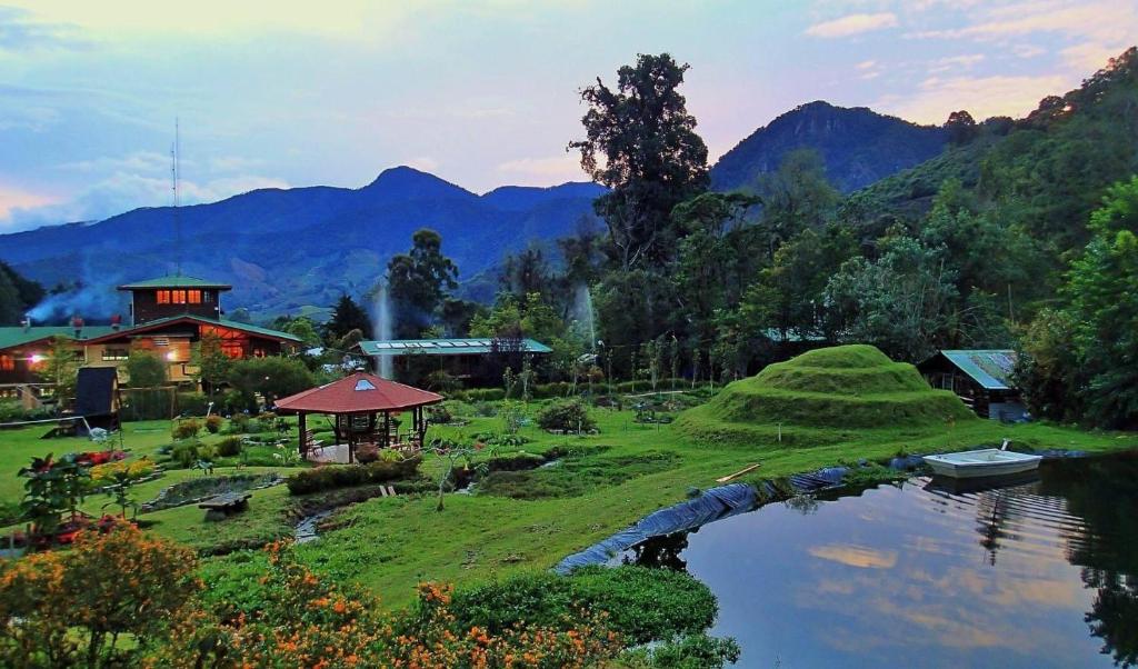 ośrodek wypoczynkowy ze stawem i górami w tle w obiekcie Los Quetzales Ecolodge & Spa w mieście Cerro Punta