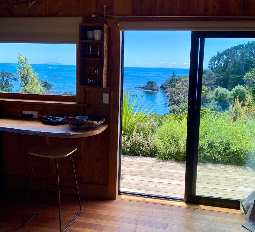 a room with a view of the ocean through a glass door at Kereru Cabin in Palm Beach