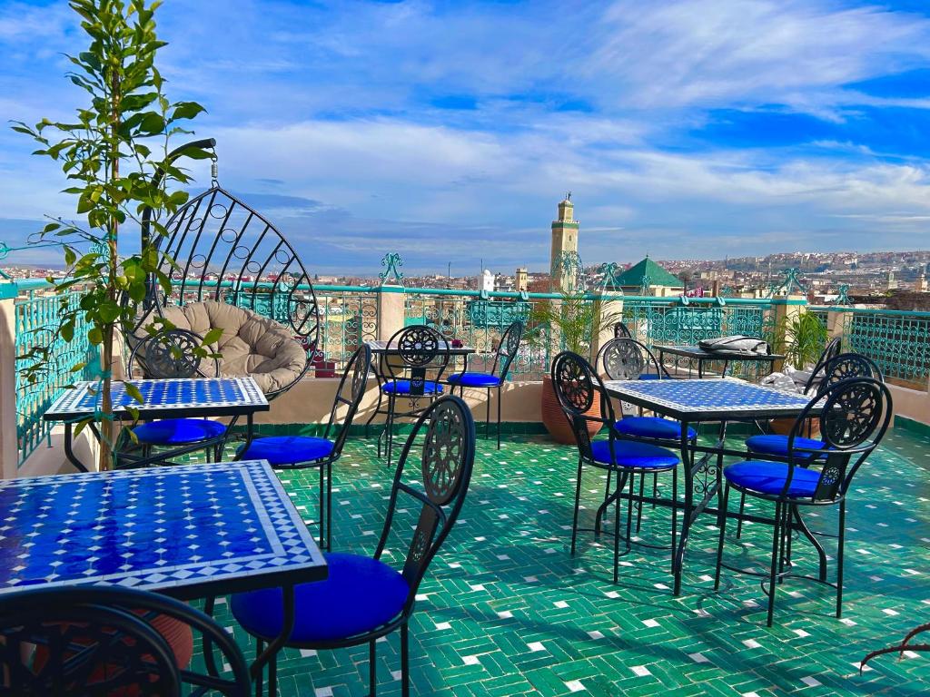 een patio met tafels en stoelen op een dak bij Riad Noor Medina in Fès