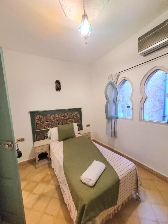 a bedroom with a bed and two windows at Honey Suckle in Chefchaouene