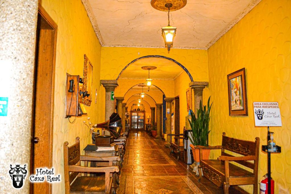 un pasillo en un edificio con paredes amarillas y mesas de madera en Hotel Caxa Real, en Comayagua