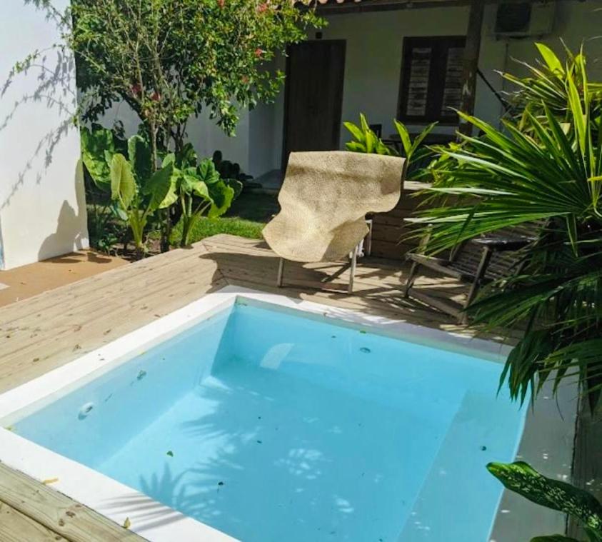 una piscina de agua en un patio con una silla en Villa Joá - Casa en Trancoso