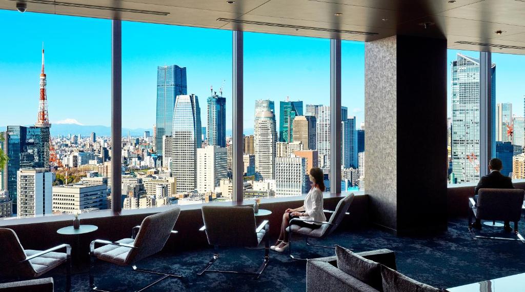 two people sitting in chairs in a room with a view of a city at Park Hotel Tokyo in Tokyo