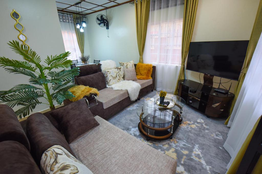 a living room with a couch and a tv at Entire 3-Bedroom Holiday Home in Kampala, Lovingly Furnished in Kampala