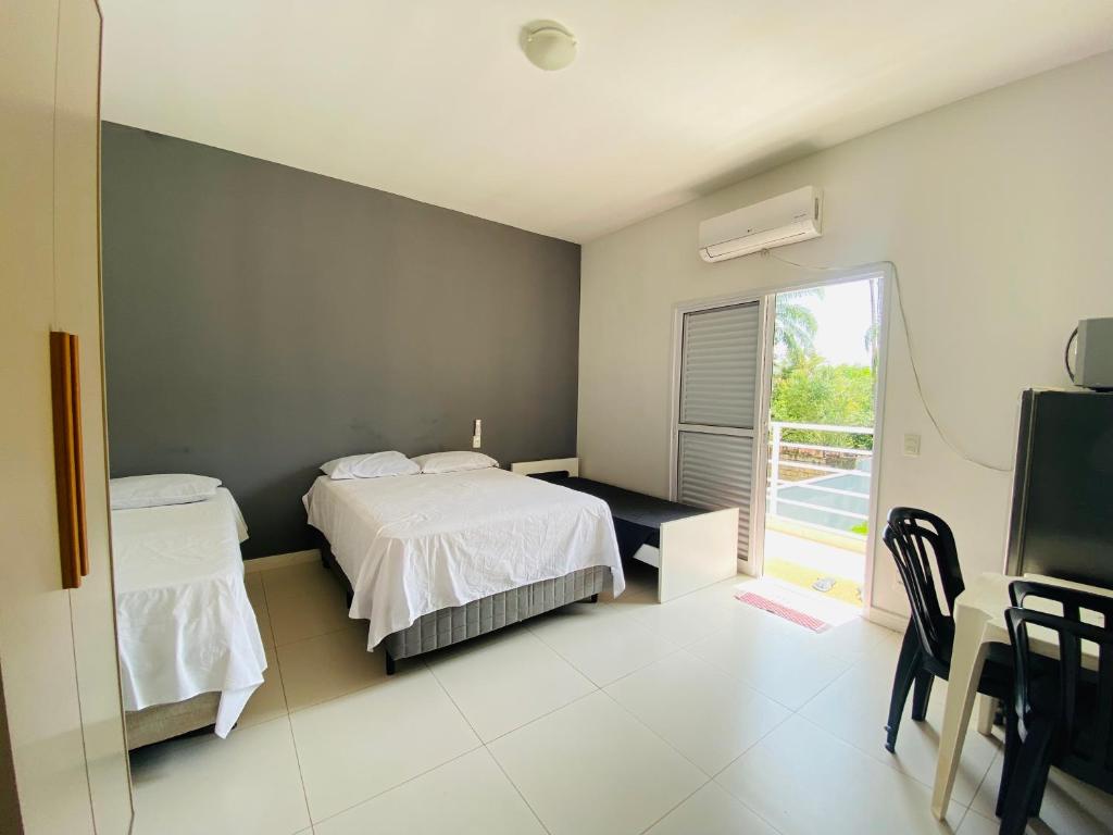 Schlafzimmer mit einem Bett, einem Schreibtisch und einem Fenster in der Unterkunft Suíte privativa proxima ao Sesc 2 in Bertioga