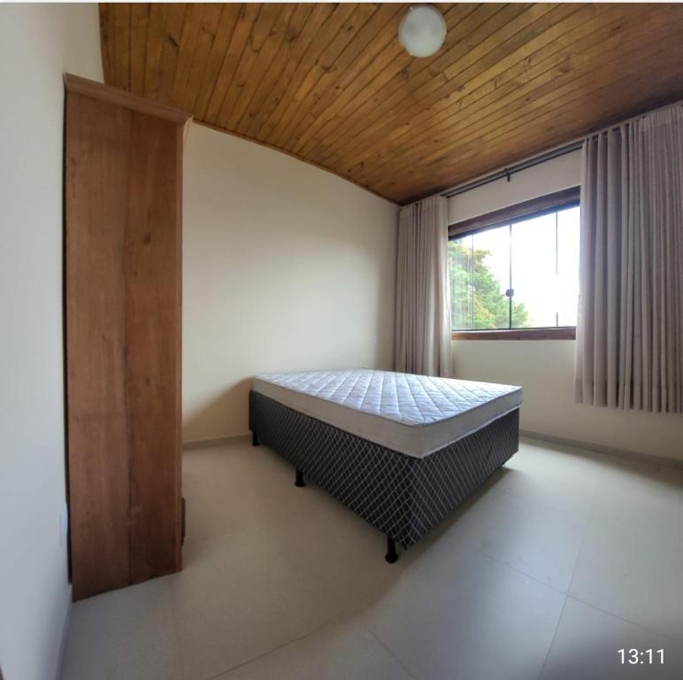 a bedroom with a bed in a room with a window at Casa Alto do Campo - Lavras Novas MG in Lavras Novas