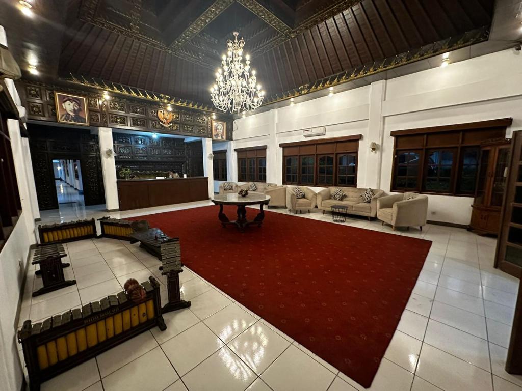 Habitación grande con sofás y alfombra roja. en Sadinah Sahid By Meliala, en Kartosuro