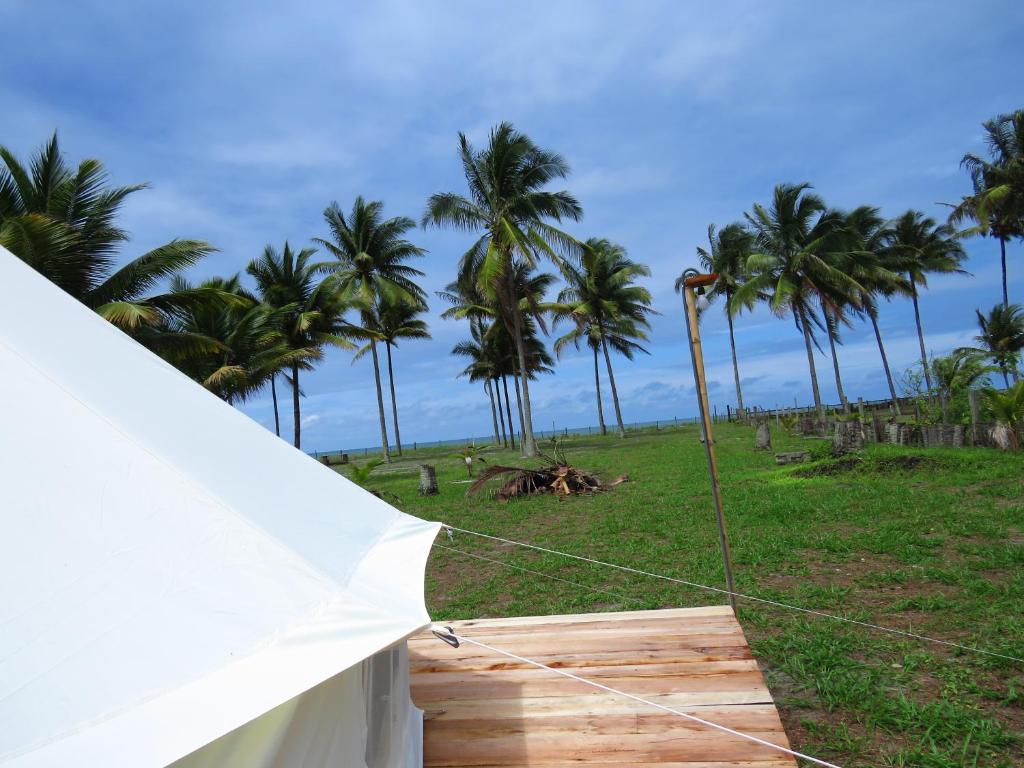une tente blanche avec des palmiers en arrière-plan dans l'établissement Glamping La Isla Bonita (Isla Portete, Ecuador), à Zapotal