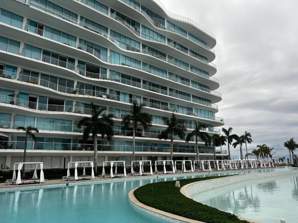un grand bâtiment avec des palmiers et une piscine dans l'établissement Maritima Playa Deluxe Ocean View Vallarta, à Nuevo Vallarta