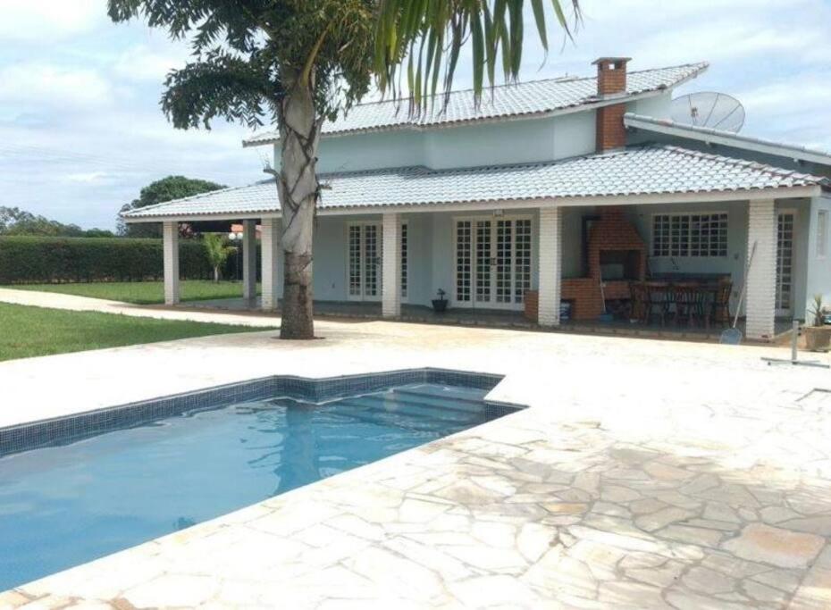 a house with a swimming pool in front of a house at Casa com piscina em condomínio ensolarada! in Santa Bárbara do Rio Pardo