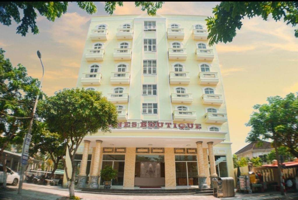 Un gran edificio blanco con árboles delante. en Zone 5 Boutique Hotel, en Da Nang