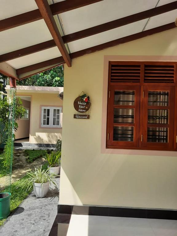 una casa con una porta di legno sul lato di Happy Nest a Talagala