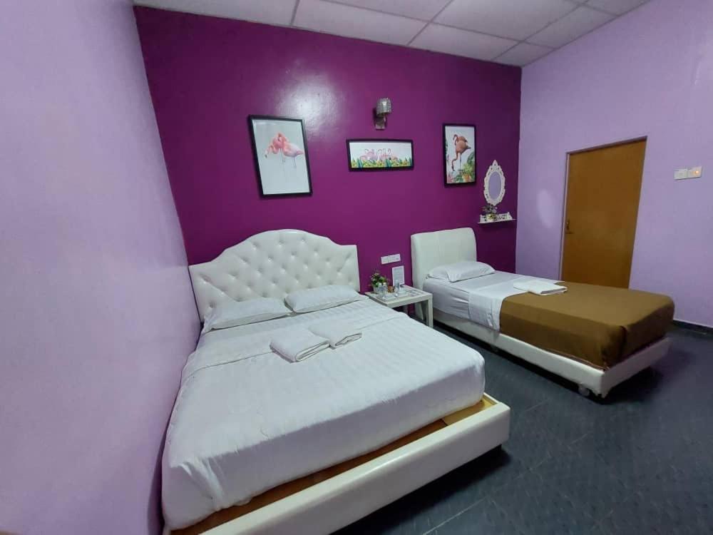 a bedroom with two beds and a purple wall at Taman Negara River View Lodge in Kuala Tahan