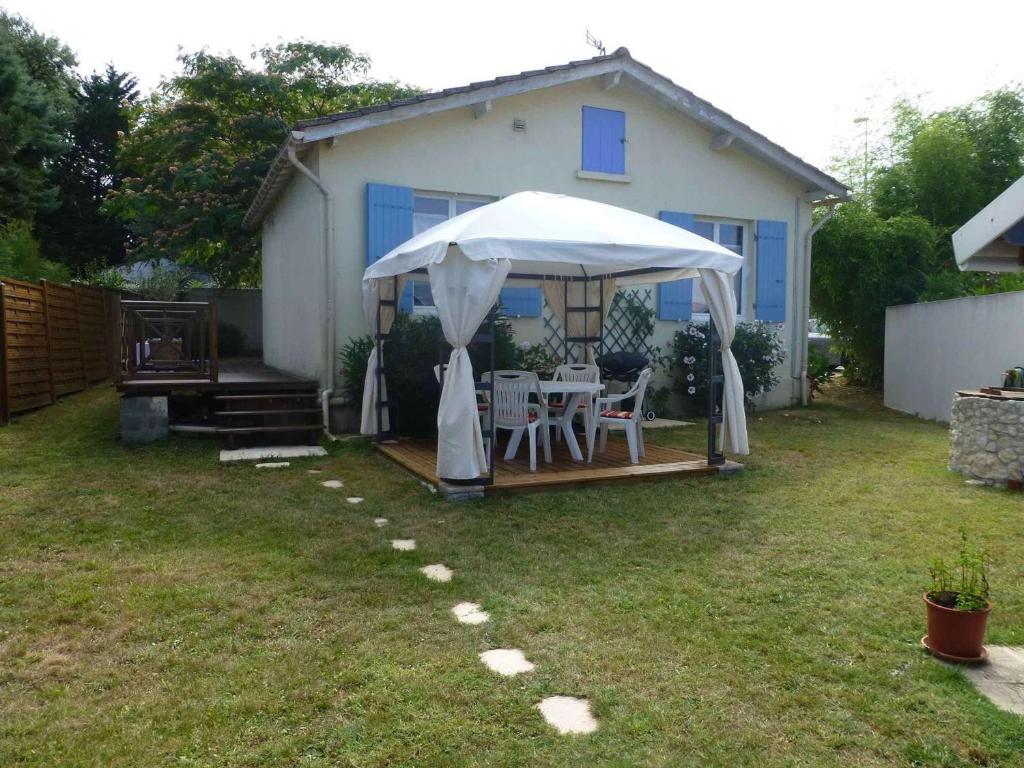 een achtertuin met een tafel en een witte paraplu bij Maison Le Grand-Village-Plage, 3 pièces, 4 personnes - FR-1-246A-314 in Grand-Village-Plage