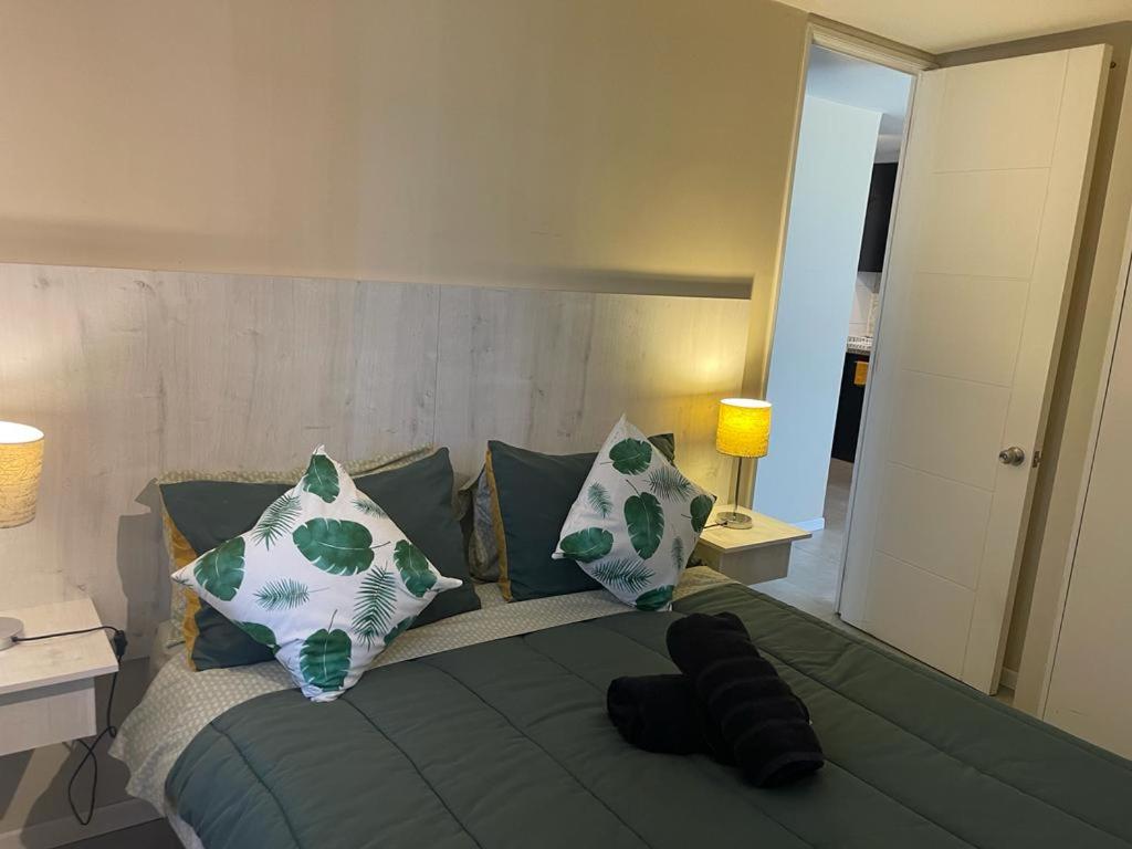 a bed with green and white pillows in a bedroom at Atalaya Apartment Suite in Santiago