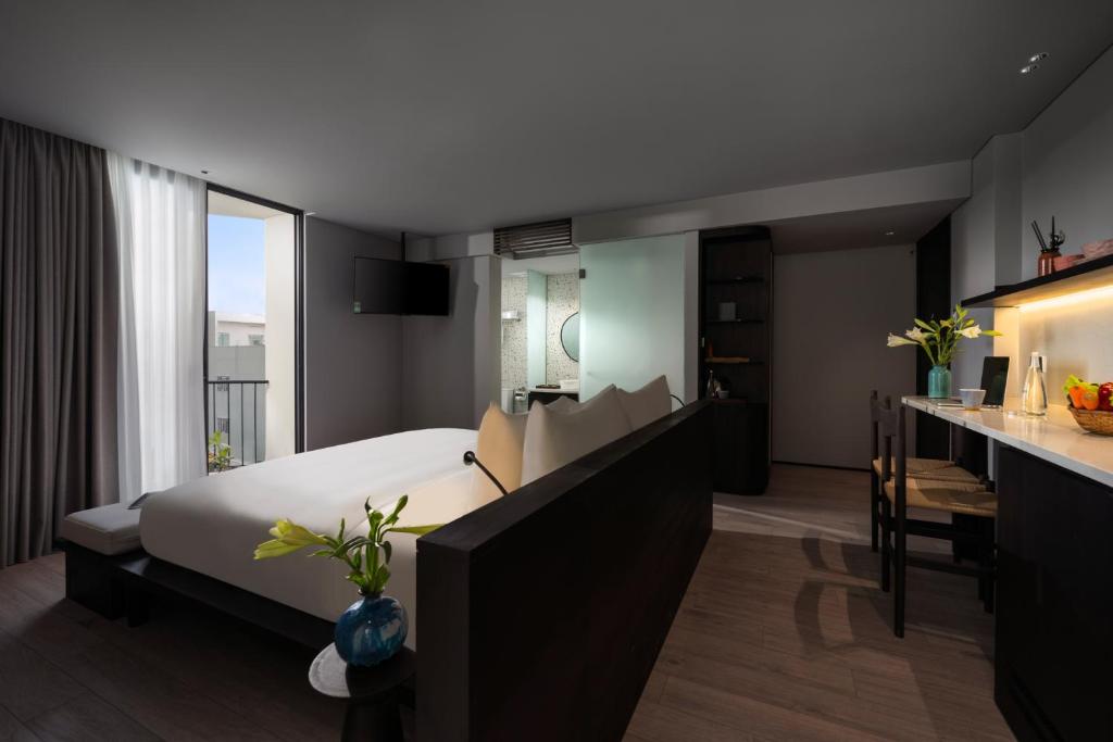 A studio-style room with a bed, kitchenette, desk and balcony doors.
