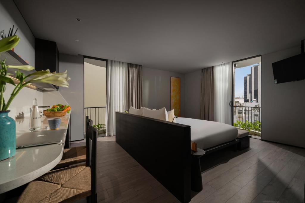 A bright hotel room with a partitioned bed, kitchenette and balcony outlook.
