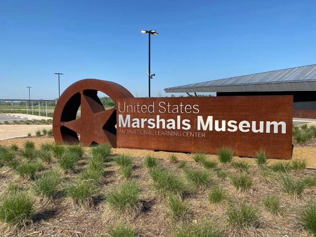 Una señal para el Museo Marshalls de los Estados Unidos en Old Fort Loft King & Queen suites nearest accomodation to Marshals Museum power your EV for free! en Fort Smith