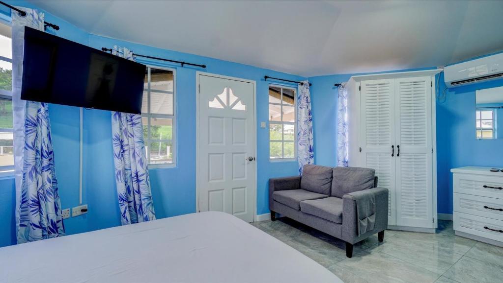 Schlafzimmer mit blauen Wänden, einem Bett und einem Stuhl in der Unterkunft Kaibus Place- Quaint Quiet and Cosy in Morne Rouge