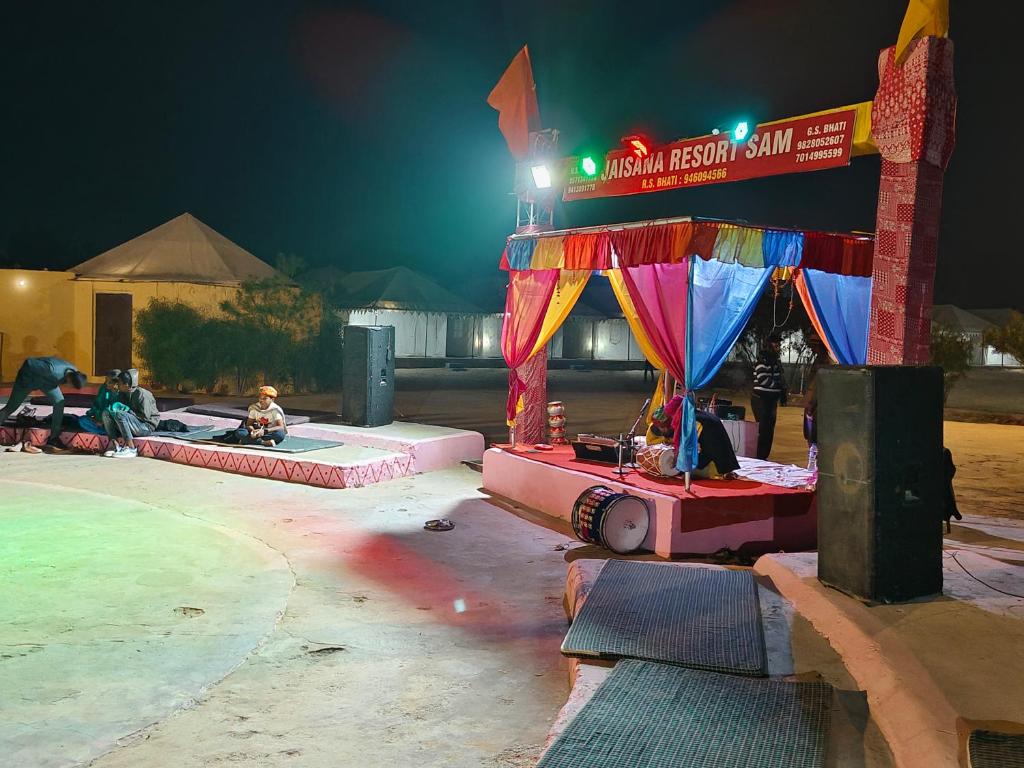 - une aire de jeux avec des personnes assises sur des bancs la nuit dans l'établissement Awar Desert Safari, à Jaisalmer
