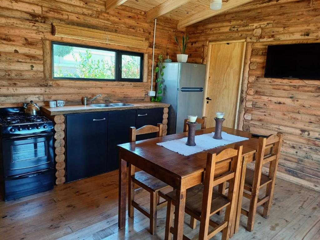 una cucina in legno con tavolo e frigorifero di Complejo de Cabañas Pura Vida a Balneario Reta
