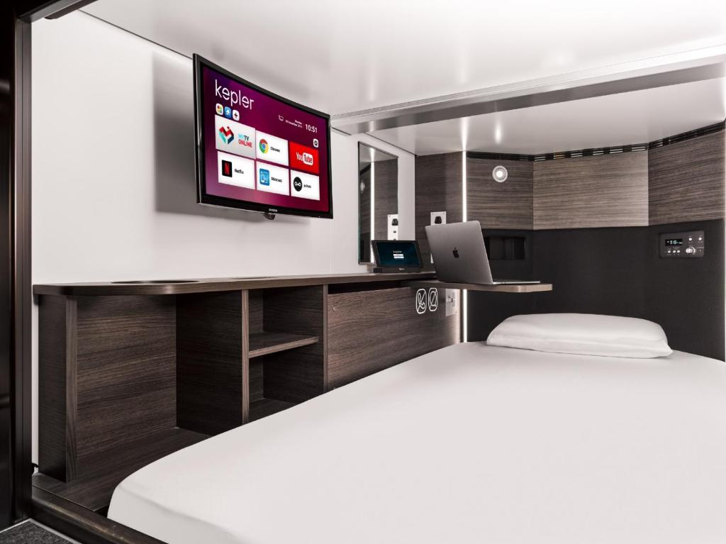 a bedroom with a bed and a tv on a wall at Kepler Club Kuala Lumpur Airport - KLIA Terminal 1 Airside Transit Hotel in Sepang