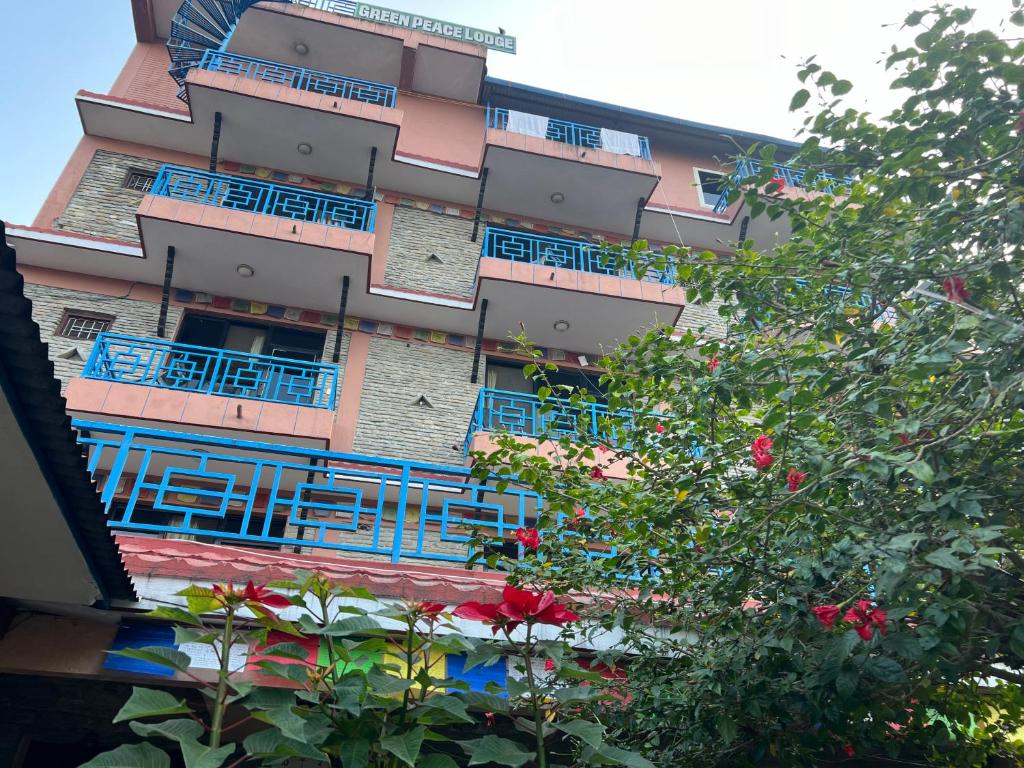 a tall building with blue balconies and a tree at Little Pilgrim Family Lodge in Pokhara