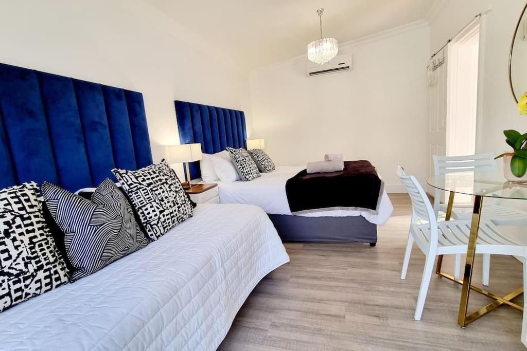 a bedroom with two beds and a table and a dining room at Cottage at 6 on Elba in Paarl