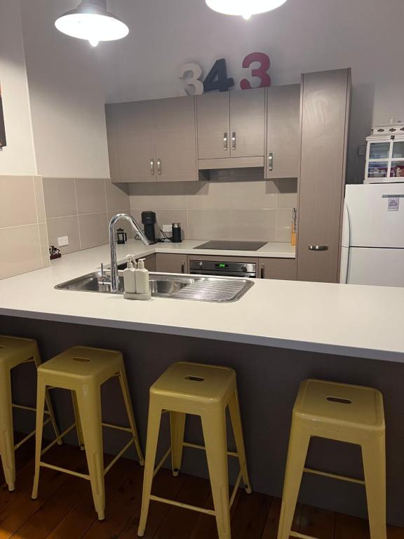 cocina con 2 taburetes amarillos y lavamanos en MURRUMBURRAH ARTHOUSE APARTMENTS en Harden