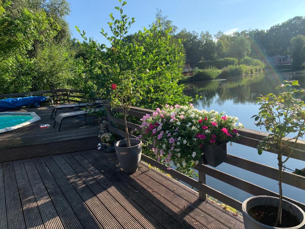 een terras met potplanten en uitzicht op een rivier bij Holiday Home 'Beautifull Water' in Lanaken
