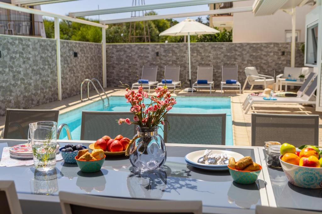 a table with a vase of fruit and flowers on it at Accomoteleia Crystal Lagoon Villa in Protaras