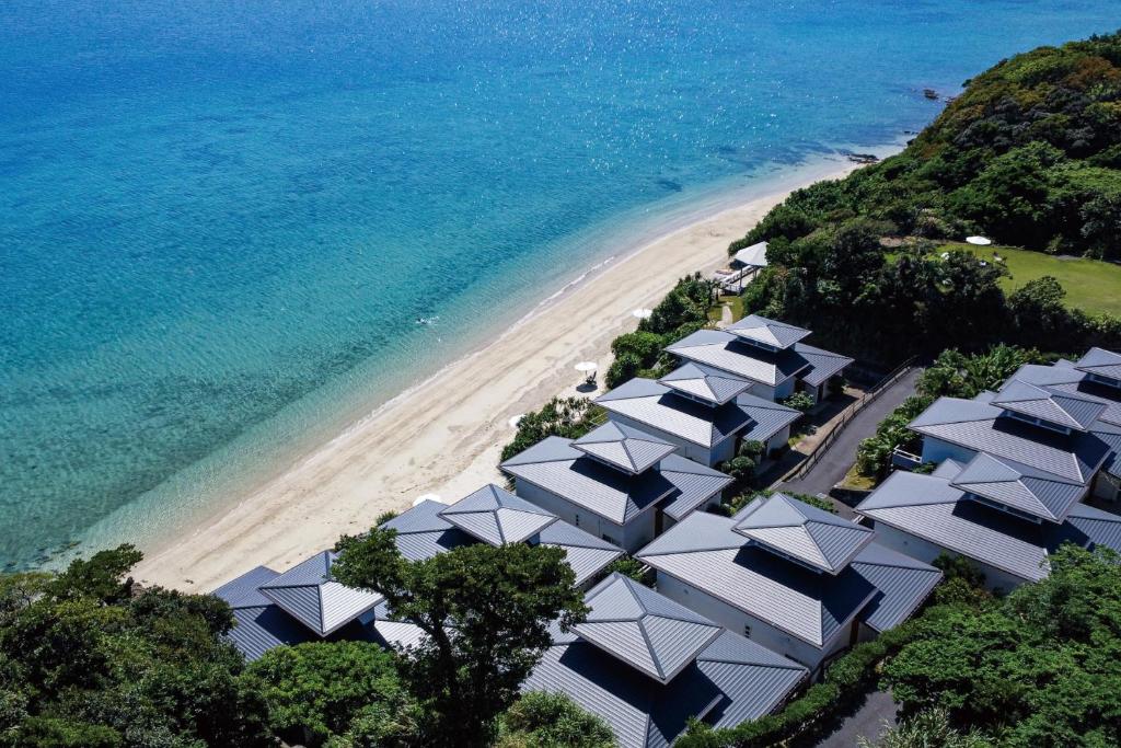 eine Luftansicht auf einen Strand mit weißen Sonnenschirmen in der Unterkunft Miru Amami in Tatsugo