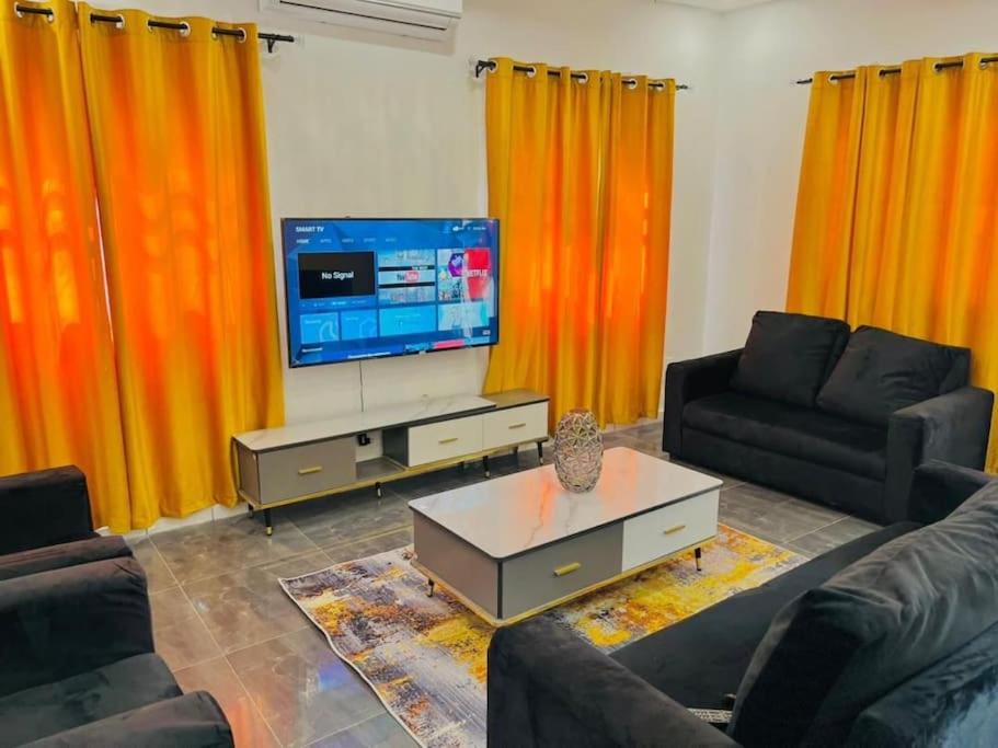 uma sala de estar com cortinas cor de laranja e uma televisão em LES 9 Plurielles T3 KPALIME KOUMA KONDA em Palimé