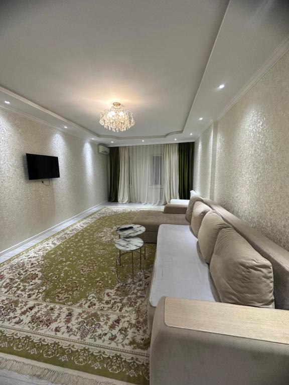 a living room with a large couch and a television at Уютные апартаменты в самом центре города на площади Исатая Махамбета in Atyraū