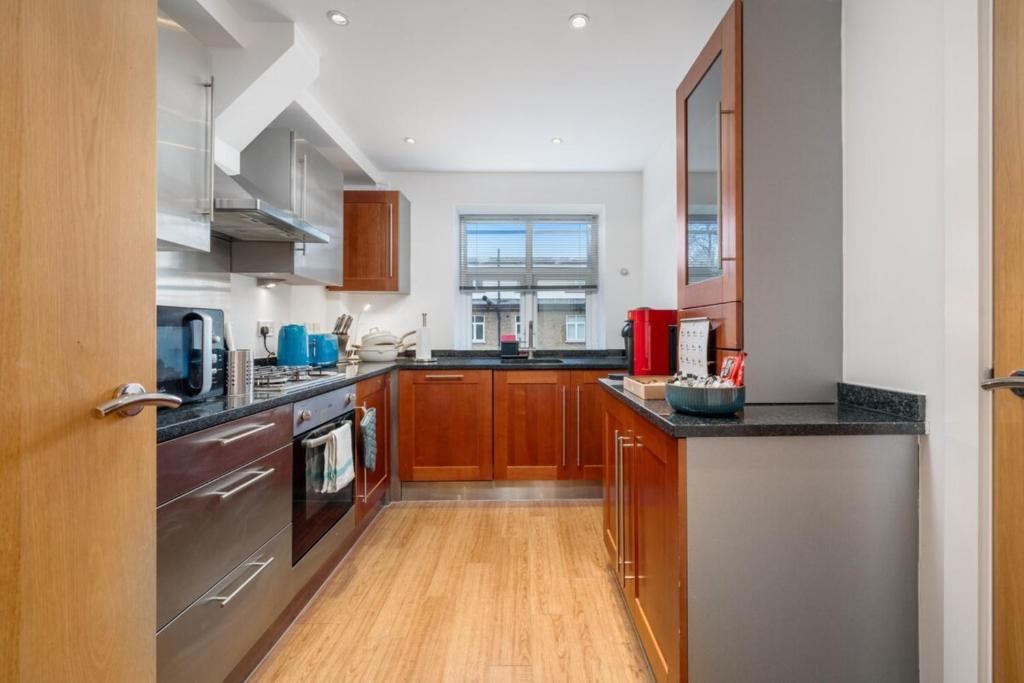 a kitchen with wooden cabinets and a stainless steel appliance at Stunning 3BD Flat Free Parking close to Greenwich in London