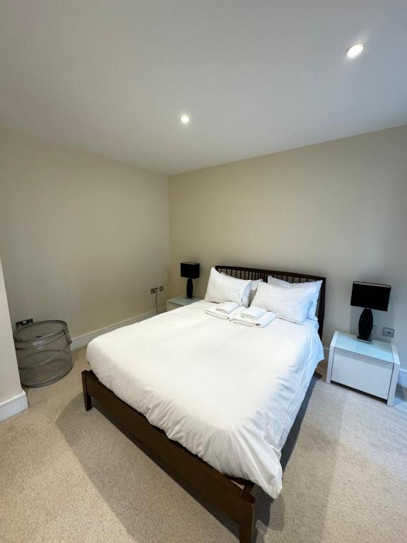 a bedroom with a large bed with white sheets at Contemporary 2BD Flat wBalcony Canary Wharf! in London